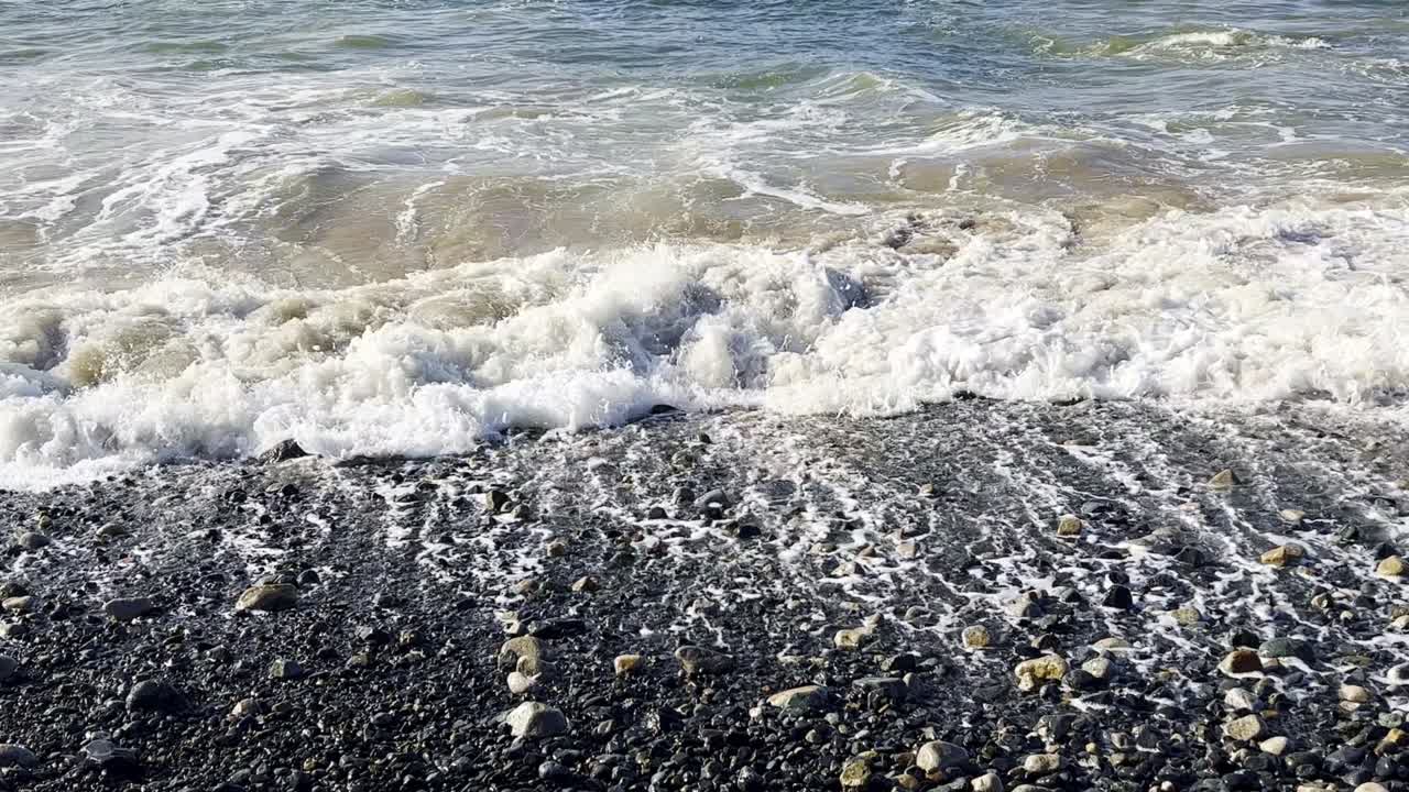 Breaking wave on pebble beach.