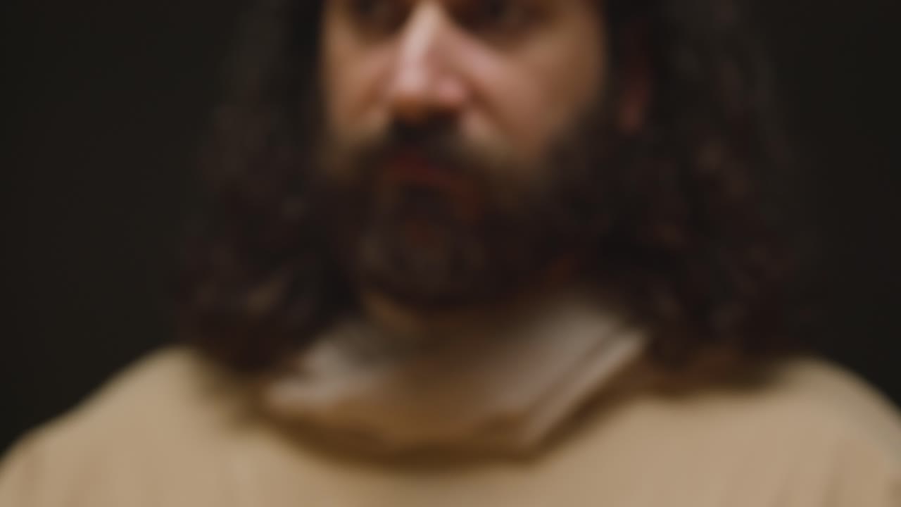 disparo de cerca de un hombre vestido con túnicas con cabello largo y barba que representa la figura de jesucristo con pan y vino predicando