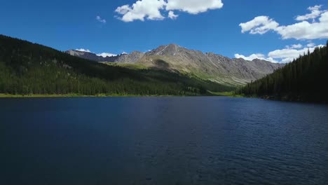 AERIAL:-Rising-above-blue-Colorado-lake-with-mountain-centered-in-the-background