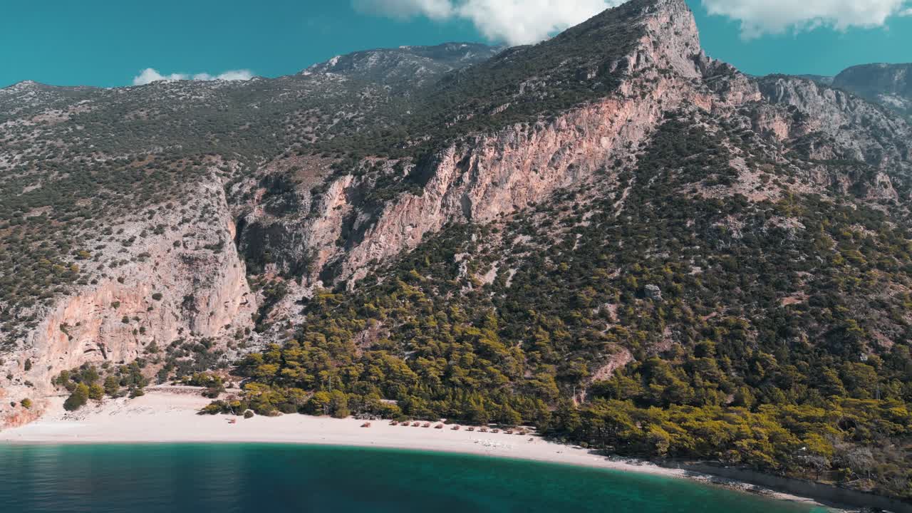 drone shot of a white sand beach in the bottom of a mountain with blue water sea - Fethiye - Turkey