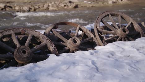 50 fps three rotten ancient museum wagon wheels placed near the flowing river