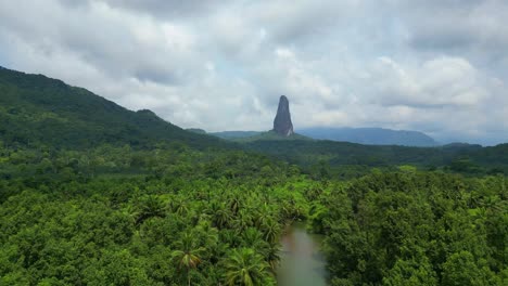 Flying-over-the-caué-river-surrounded-by-the-green-forest-towards-the-peak-Cão-Grande-an-elevation-of-volcanic-origin