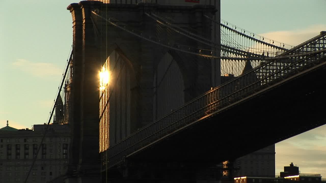 la luz del sol de un edificio detrás del puente de brooklyn brilla a través de la infraestructura para crear una hermosa foto