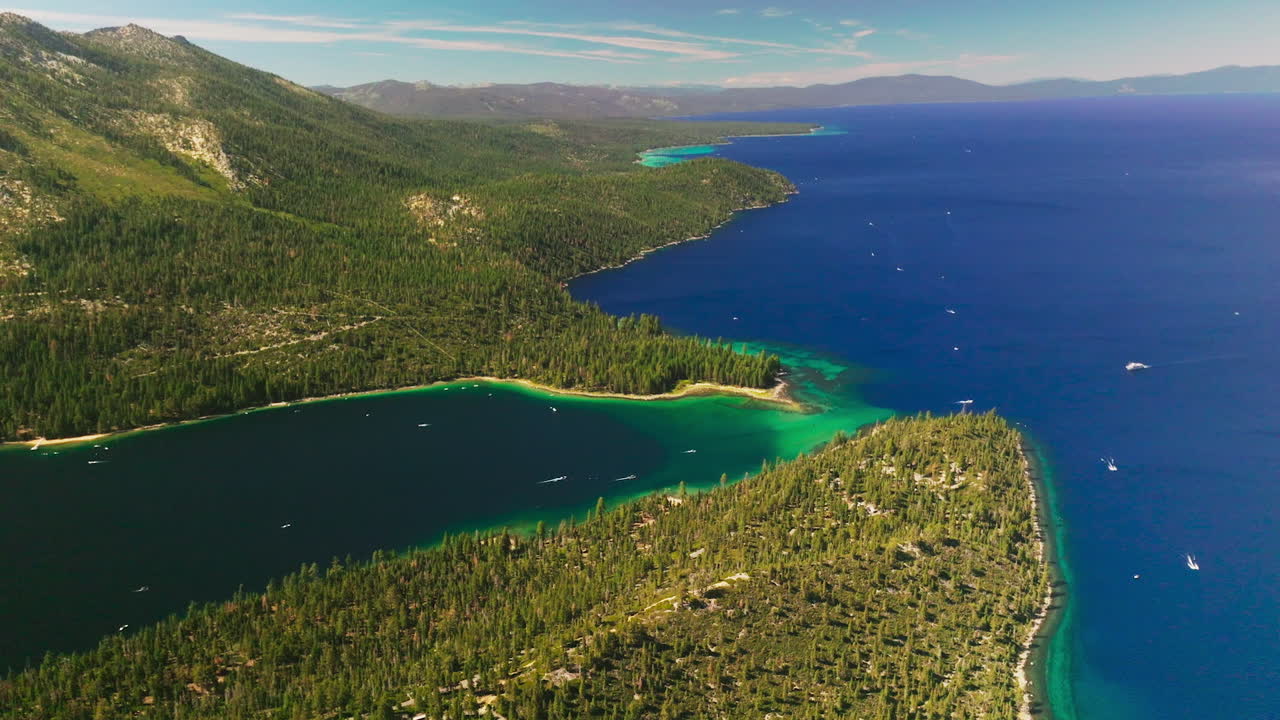 Different shades of blue in the waters of Lake Tahoe, California, USA. Amazing scenery of the lake and rocky wooded shore from aerial view.