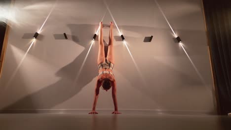 young female athlete doing a handstand in a studio