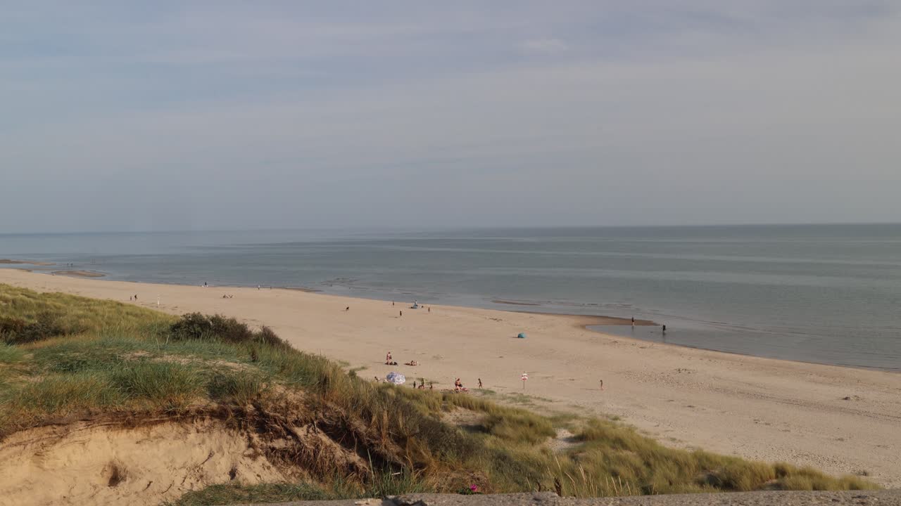 People on a sandy beach below sand dunes in Denmark, east coast