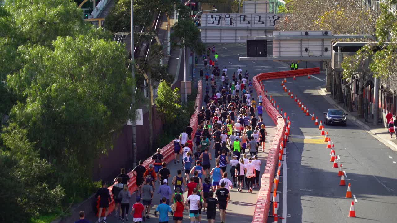 People participating in a running contest. The race takes place on the streets in the middle of the city. Bright, sunny day.