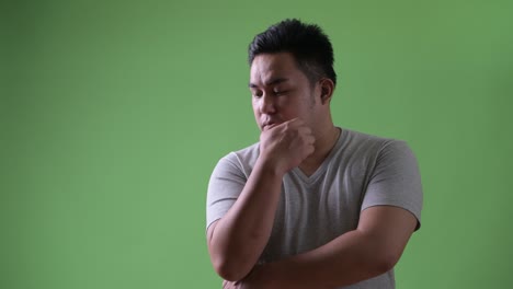 young handsome overweight asian man against green background