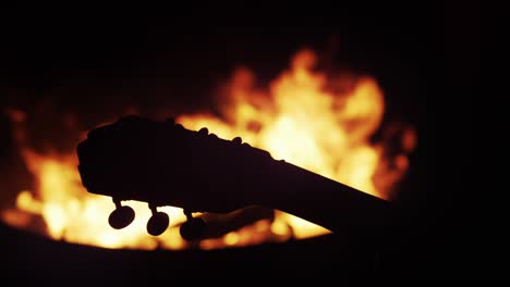 guitar neck silhouetted at bonfire