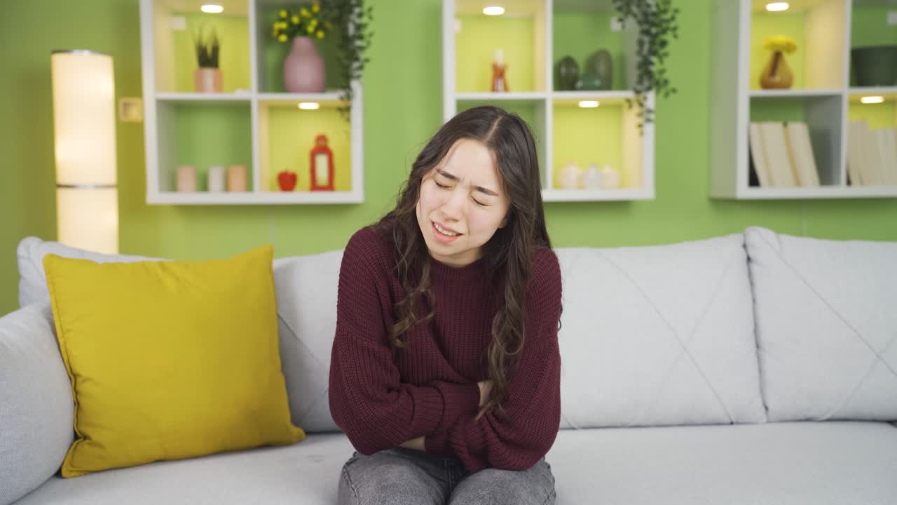 복통이 있는 아시아 젊은 여성이 통증을  ⁇ 고 있습니다.