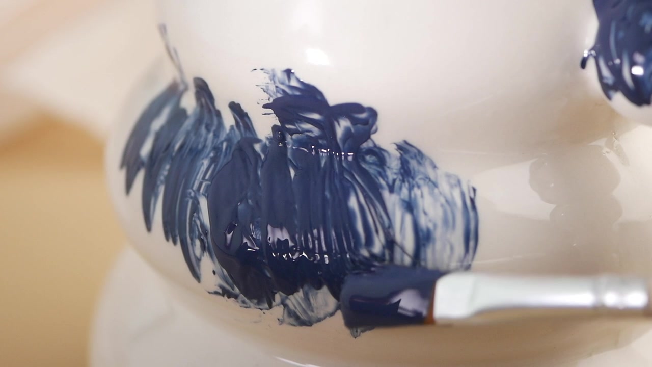 Artista che dipinge pennellate blu su ceramica bianca