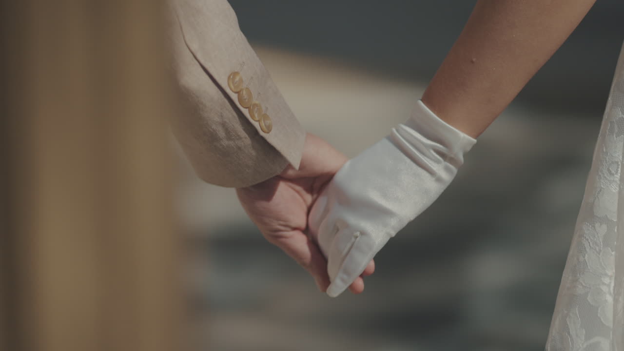 Close-Up of a Couple Holding Hands in a Romantic Gesture, Featuring Elegant Attire and White Glove.