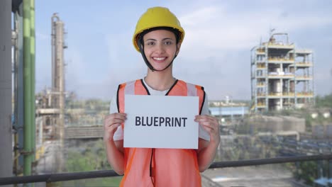 happy indian female construction worker holding blueprint banner