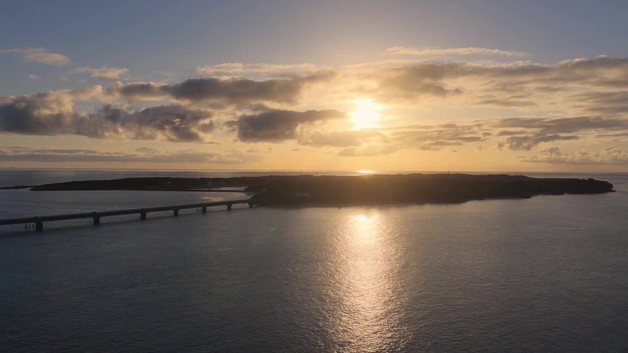 Horizontal cameo trucking right while facing left from a lateral angle toward Ikema Island Bridge at sunset, Miyako, Okinawa, Japan