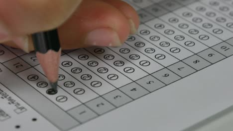 student hand filling out in answer sheet with standardized test form