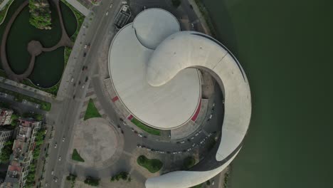 aerial view of modern curved building by water in urban setting