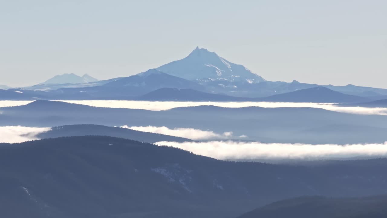 遠くに成層火山ジェファーソン山、密集した松林、雲海を捉えた、DJI Mavic 3 Proでマウント・フッド国立森林公園で撮影された、ズームパン航空ドローンショット。