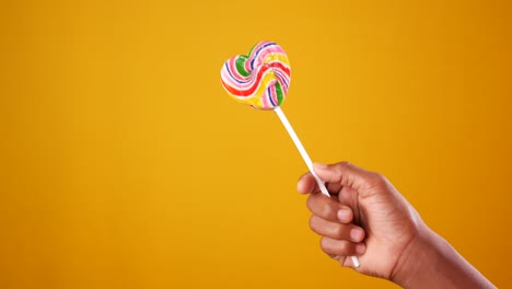 hand holding colorful heart-shaped lollipop