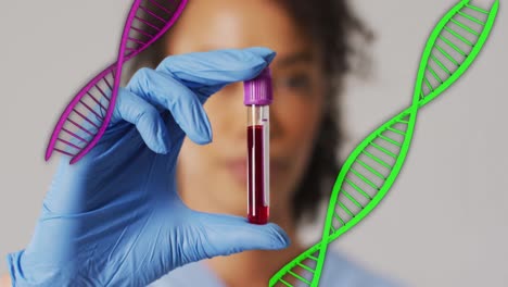 Animation-of-dna-strands-over-african-american-female-doctor-holding-vial-with-liquid