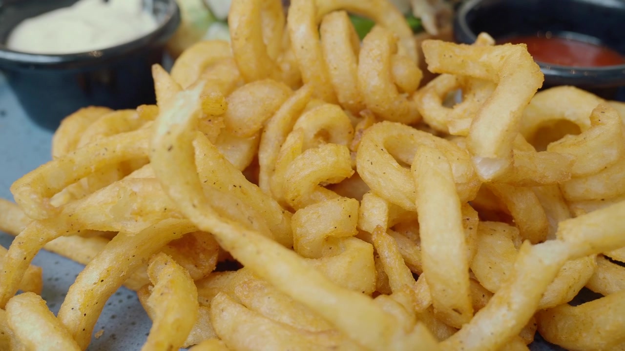 Primer plano de patatas fritas rizadas crujientes en un plato