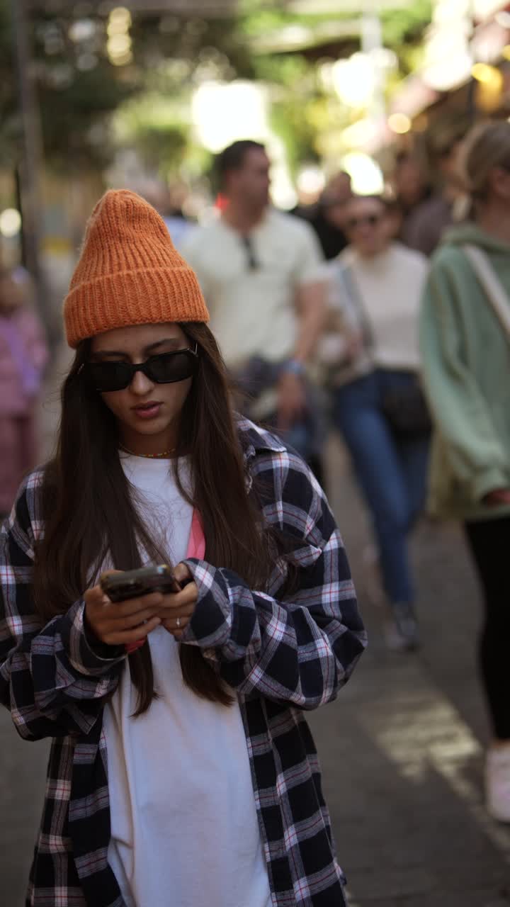 adolescente caminando y mirando el teléfono en la ciudad