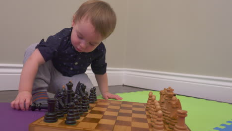 curious toddler boy playing with chess pieces