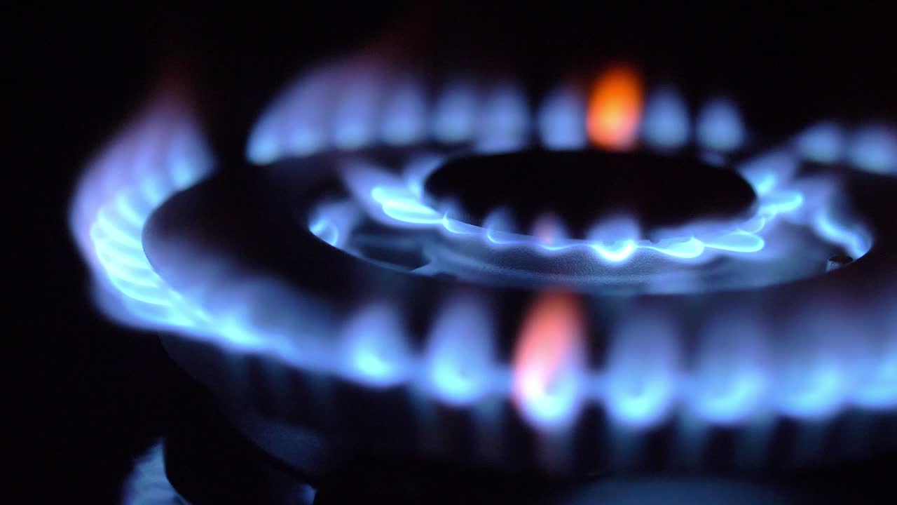 가스 스토브가 켜지고 꺼지고 파란 불꽃이 어 속에서 불타고 있습니다.