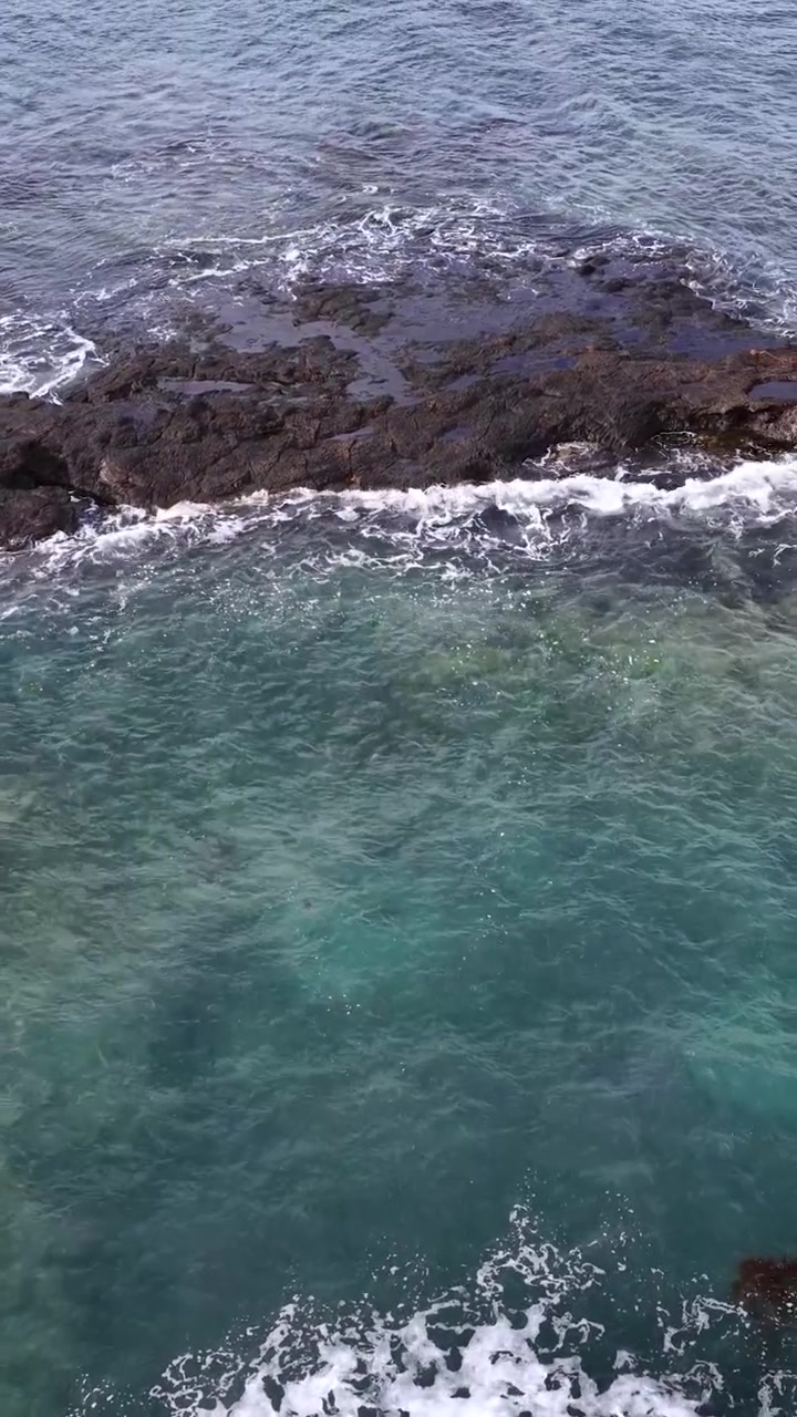 Pemandangan sudut tinggi air pirus dan buih laut putih menghantam pantai berbatu di Flinders, Australia.