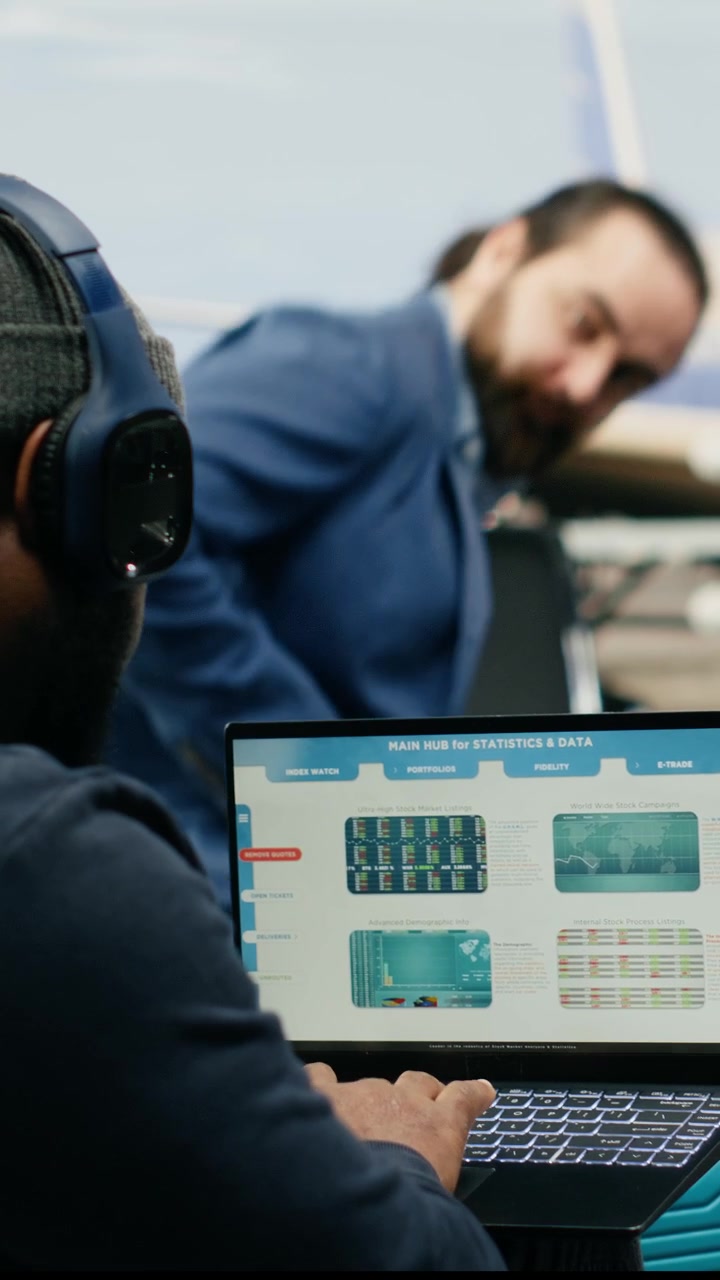 Video verticale: Lavoratore di colore informale che controlla insight e analisi sul laptop in una lounge aeroportuale