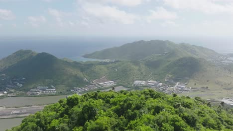 Drone-view-revealing-Grand-Case-Airport-on-Saint-Martin-with-beautiful-hills-covered-with-greenery-in-Carribean-Island