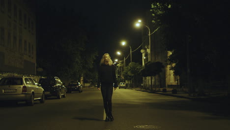 mujer caminando sola por la noche con ropa casual en la carretera de la ciudad.