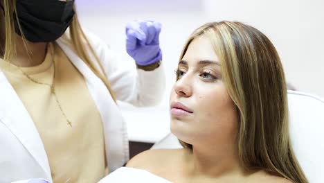 crop anonymous beautician injecting botox in female face