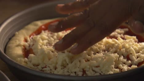 espolvoreando queso a mano sobre base de tomate sobre base de pizza