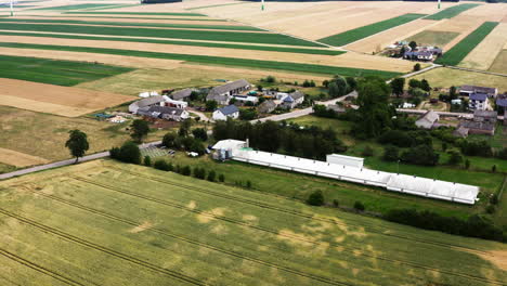 polish village with poultry farm surrounded by vast fields in summer. - aerial shot