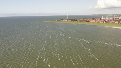 aerial shot approaching the scenic coastal town of hindeloopen in friesland, the netherlands, on a beautiful sunny summer day