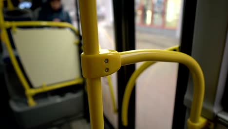 the bus doors close and the bus pulls away from the stop. close-up of the yellow handrail. view from inside the bus. blurred background. 4k