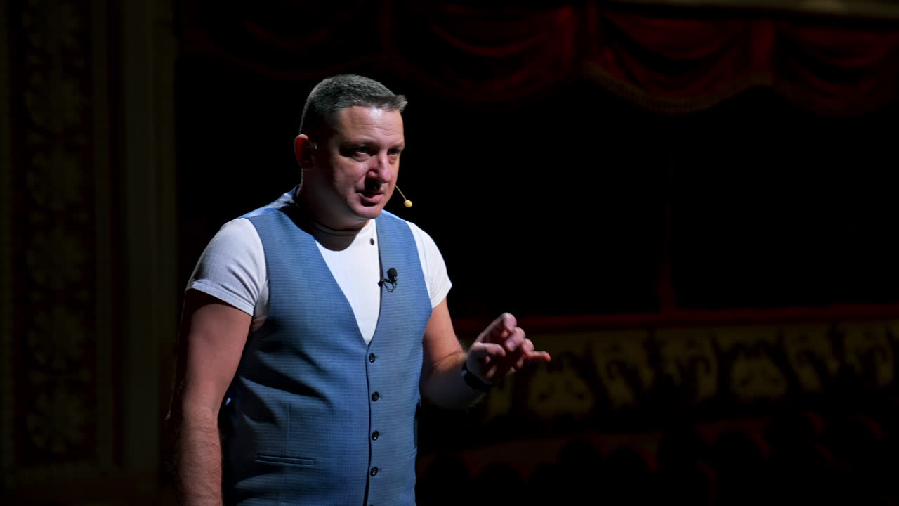 Actor on classic theatre stage. Man is speaking in spotlights during the performance. Side view video.