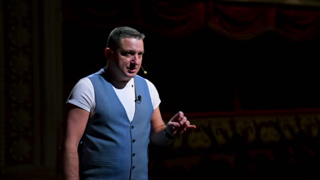 actor on classic theatre stage. man is speaking in spotlights during the performance. side view video.