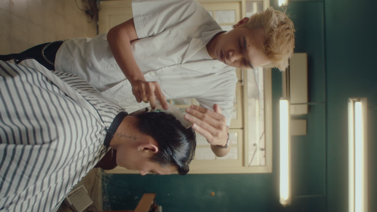 Young Asian Barber Brushing Hair of Client with Comb