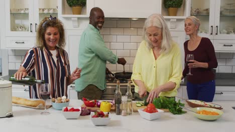 animation of happy diverse female and male senior friends preparing meal in kitchen