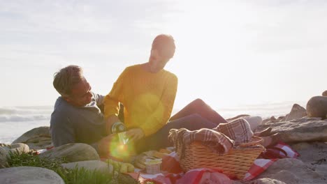 caucasian couple enjoying free time by sea on sunny day eating and drinking coffee