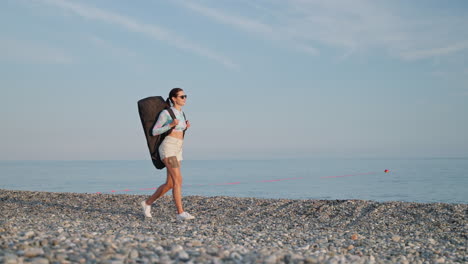 woman with backpack walking on a pebble beach