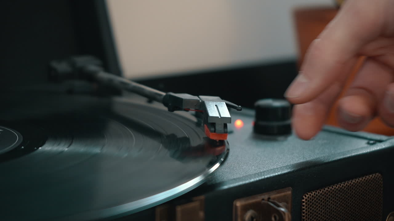 A hand places the needle on a spinning record on a turntable.