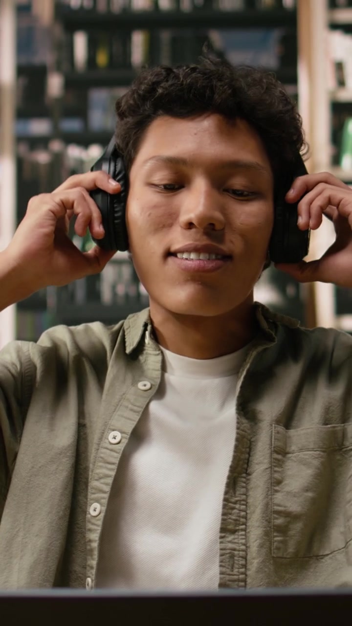 Vertical Video Student With Headphones Reading Open Book And Studying With Focus Music