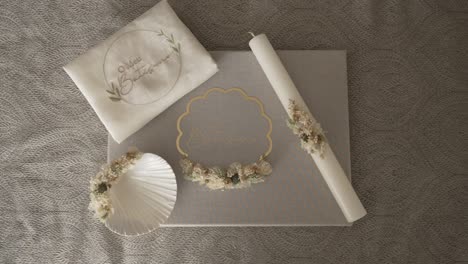baptismal candle towel seashell and dried flower items arranged for religious ceremony