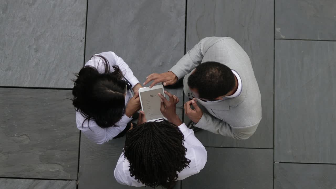 Three people standing on street and looking at tablet
