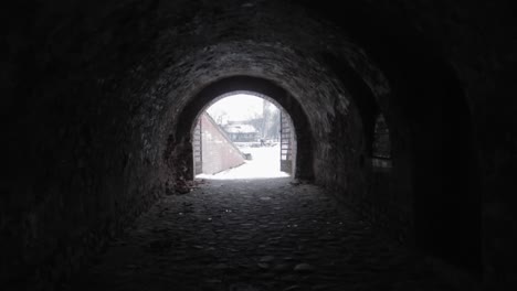 walking slowly in a dark black tunnel towards the entrance shining brightly in the distance