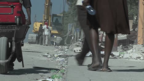 people walk amongst the rubble following a devastating earthquake in haiti