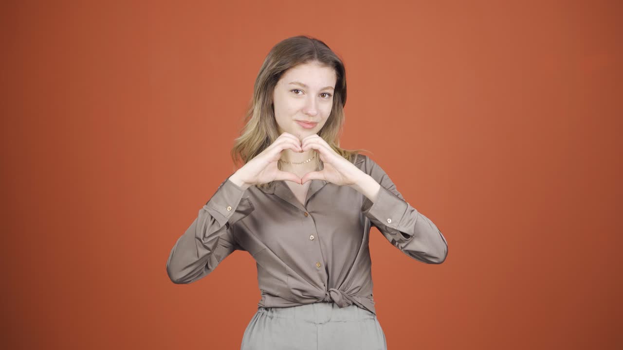 자신감의 표시를 하는 카메라를 보는 젊은 여성.