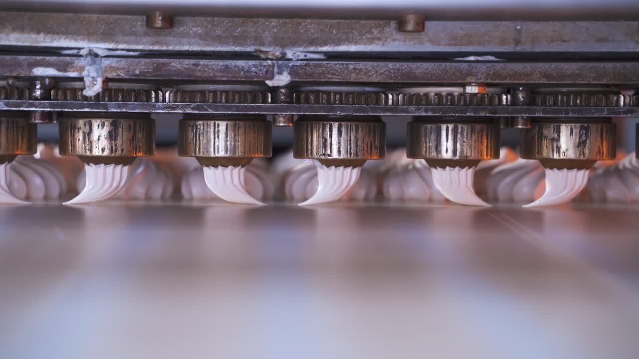 Produzione di marshmallow. Soufflé con una bocchetta da pasticceria. Macchina automatica per la produzione di prodotti dolciari in una fabbrica alimentare